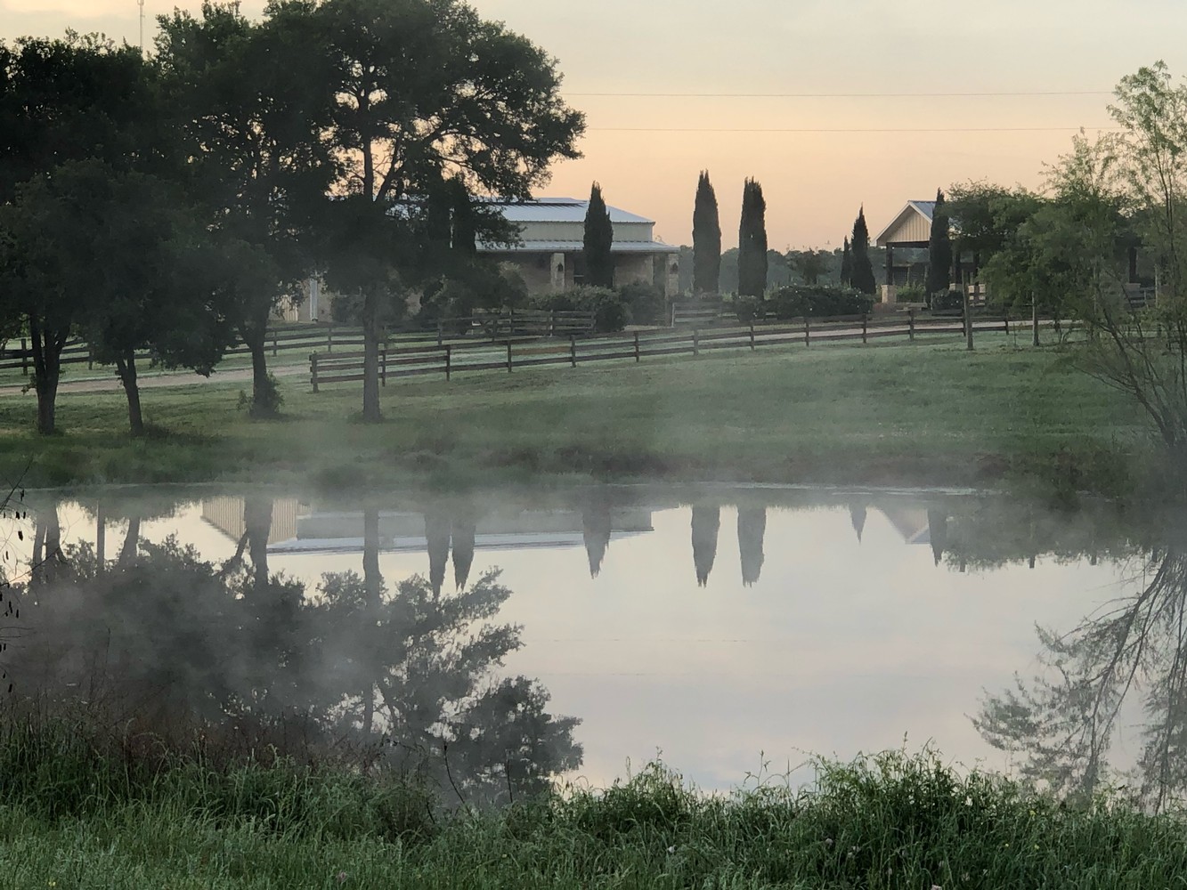 Still water reflecting trees and estate buildings at Red Rock Vineyards